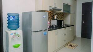 A compact kitchen with a refrigerator, a water dispenser, a microwave, and a stove.