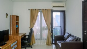 A modern living room with a wooden desk, a black office chair, a leather sofa, and a large window with curtains.