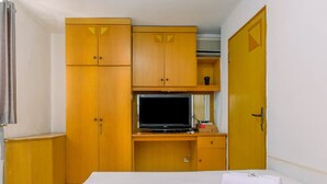A bedroom with a bed, a television, wooden wardrobes, and a door. - New Furnished 1BR Rajawali Apartment (Jakarta)