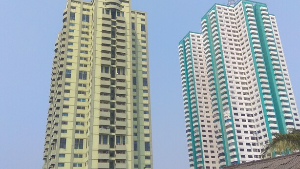 Two high-rise buildings with multiple balconies and a clear sky. - New Furnished 1BR Rajawali Apartment (Jakarta)