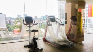 A gym with exercise equipment, large windows, and a city view. - Modern and Tidy Studio Apartment at Elpis Residence (Jakarta)