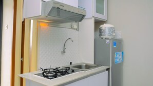 Eine kleine Küche mit Gaskochfeld, Spüle und Kühlschrank.