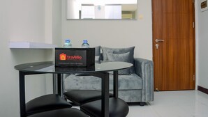 Ein Zimmer mit einem grauen Sofa, einem kleinen runden Tisch mit einer Aufbewahrungsbox mit dem Aufdruck 'Travelio' und einer Holztür.
