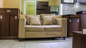 A living room with a sofa, wooden cabinets, and a tiled backsplash.