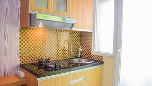 Een keuken met houten kastjes, een zwart aanrecht, een roestvrijstalen spoelbak en een Modena afzuigkap.