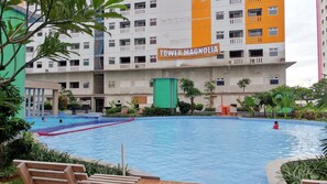 Relax by the hotel's large rectangular pool surrounded by lush greenery and comfortable benches.