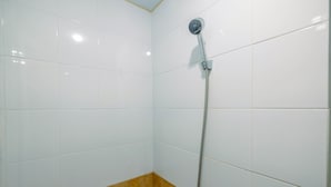 Casa de banho com paredes revestidas a azulejos brancos e um canto com azulejos castanhos.