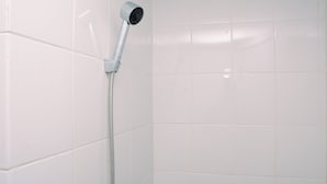 Een douche met een handdouche en flexibele slang, bevestigd aan een betegelde muur.