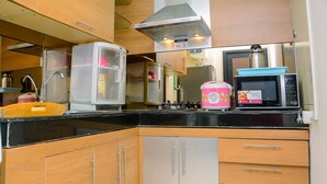 Une cuisine compacte avec des meubles en bois, une hotte en acier inoxydable, un four à micro-ondes et un cuiseur à riz rose.