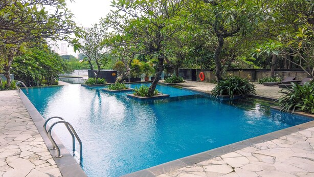 Une piscine à l’eau d’un bleu cristallin, entourée d’une végétation luxuriante et bordée de pierres.
