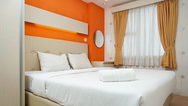 A hotel room with a large bed, a bedside table, and a wall-mounted clock. - Functional and Compact 1BR Belmont Apartment (Jakarta)