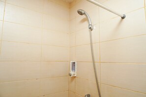 Ein geflieselter Duschbereich mit Handbrause und einer an der Wand montierten Bedienung.