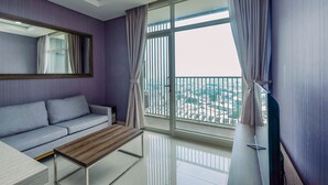 A modern living room with a sofa, a coffee table, and a large window with curtains. - Spacious 2BR at Ciputra International Apartment (Jakarta)