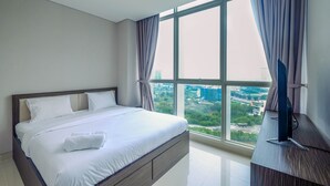A modern hotel room with a large bed, a flat-screen TV, and a view of the cityscape through large windows. - Spacious 2BR at Ciputra International Apartment (Jakarta)
