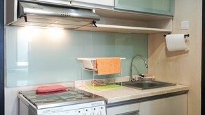 Een kleine keuken met een gasfornuis, een spoelbak en een klein aanrecht.