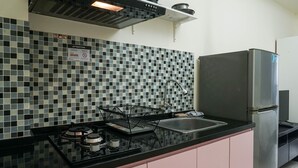 Una cocina con encimera negra, electrodomésticos de acero inoxidable y salpicadero de azulejos.