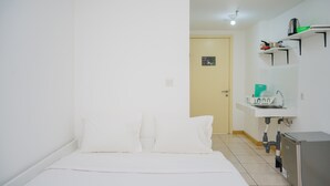 Una habitación de hotel con cama, lavamanos y una pequeña kitchenette.
