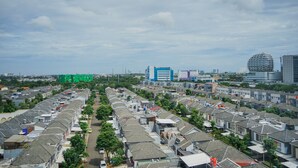 A residential area with uniform houses, a main road, and distant modern buildings. - Minimalist Studio at Beverly 90210 Apartment (Gading Serpong)