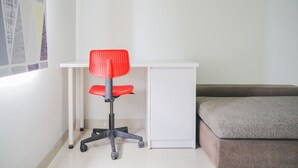 A small, white desk with a red office chair and a grey cushioned bench. - Minimalist Studio at Beverly 90210 Apartment (Gading Serpong)