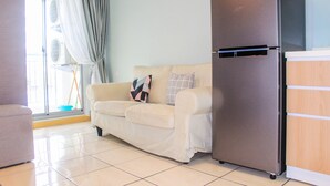 Un salon avec un canapé beige, un réfrigérateur en acier inoxydable et un meuble en bois.