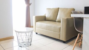 A modern living room with a beige sofa, a round wireframe table, and a white marble coffee table. - New Furnished with City View 2BR Apartment M-Town Residence (Gading Serpong)