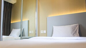 A hotel room with a large bed, a mirror, and a wall-mounted light fixture. - New Furnished with City View 2BR Apartment M-Town Residence (Gading Serpong)
