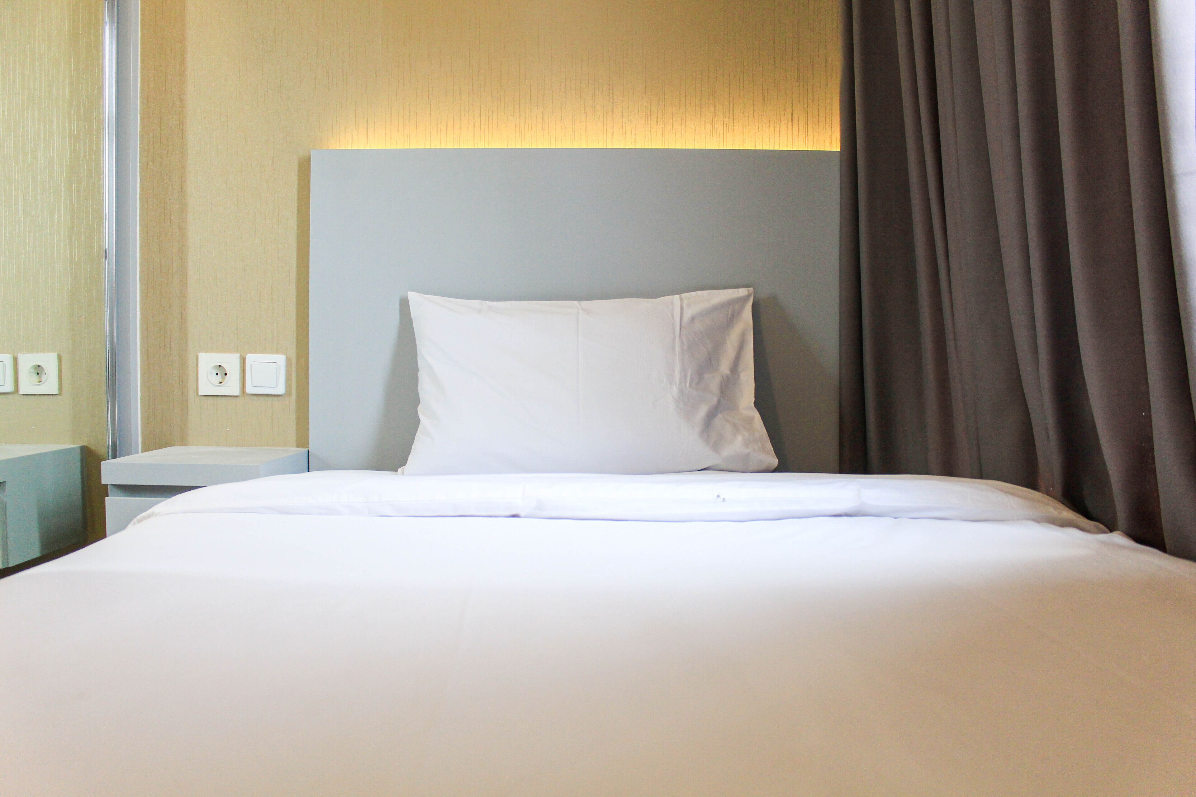 Un lit bien fait, avec du linge de lit blanc, dans une chambre d’hôtel.