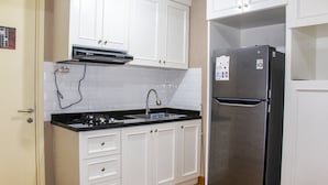 Una cocina con armarios blancos, un refrigerador de acero inoxidable y una encimera negra.
