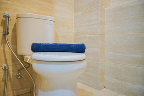 A toilet with a blue towel on top, a shower hose, and a toilet tank labeled "Acefan." - Minimalist and Comfy Studio Springwood Apartment (Tangerang)