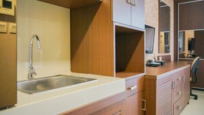 A modern kitchen with a stainless steel sink, wooden cabinets, and a countertop. - Compact and Cozy Studio Atria Apartment (Gading Serpong)