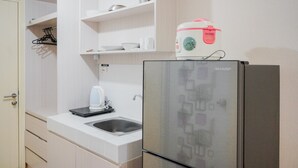 A kitchen with a stainless steel refrigerator, a kettle, and a sink. - Minimalist Studio Apartment with City View at M-Town Residence (Gading Serpong)