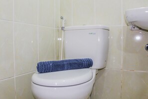 Inodoro con una toalla azul sobre el asiento y el nombre de la marca visible en el tanque.