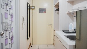 A compact kitchen with a beige door, a white countertop, and a kettle. - Minimalist Studio Apartment with City View at M-Town Residence (Gading Serpong)