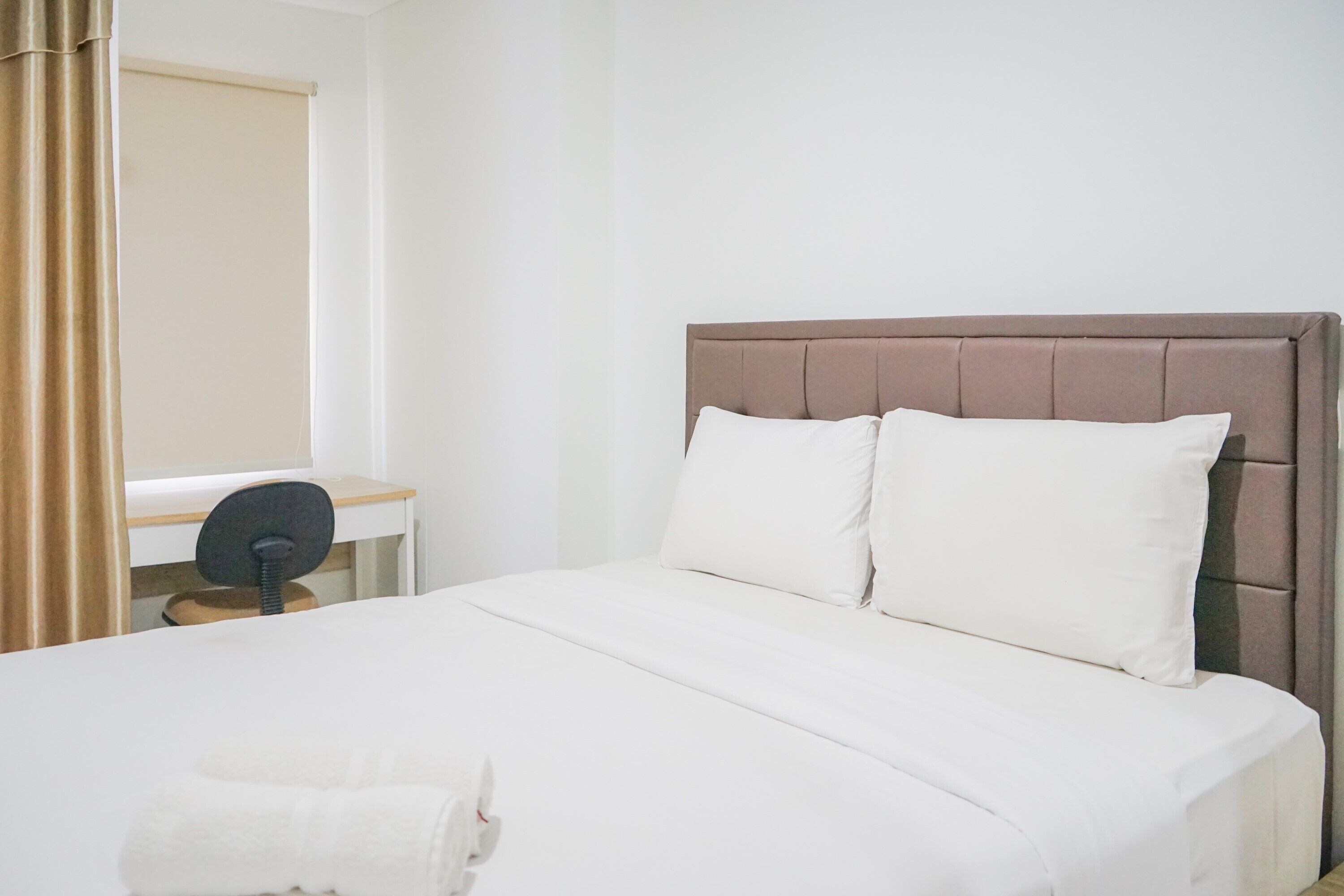 A clean, modern hotel room with a large bed, a desk, and a chair.