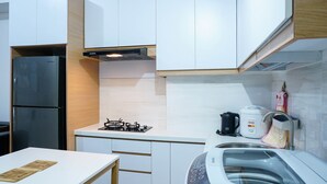 A modern kitchen with white cabinets, a black refrigerator, a gas stove, a coffee maker, and a sink.