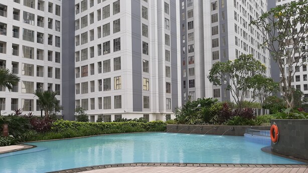 A modern residential building with a swimming pool and surrounding greenery.