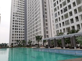 Un edificio de gran altura con varios pisos, piscina y zonas verdes circundantes.