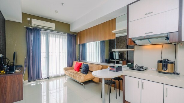 A modern kitchen with a dining area, a sofa, and an air conditioning unit. - Comfy and Minimalist 1BR Apartment at Atria Residence (Gading Serpong)