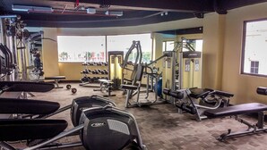 A gym with various exercise equipment, including treadmills, weight machines, and dumbbells. - Comfy and Minimalist 1BR Apartment at Atria Residence (Gading Serpong)