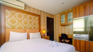A hotel room with a large bed, a desk, a wardrobe, and an air conditioning unit. - Comfy and Minimalist 1BR Apartment at Atria Residence (Gading Serpong)
