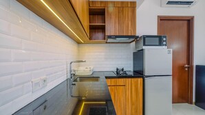 A modern kitchen with wooden cabinets, a stainless steel sink, and a built-in microwave. - Brand New 1BR Apartment at M-Town Signature (Gading Serpong)