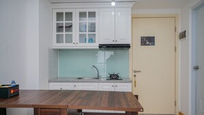 A kitchen with white cabinets, a stainless steel sink, and a wooden table.