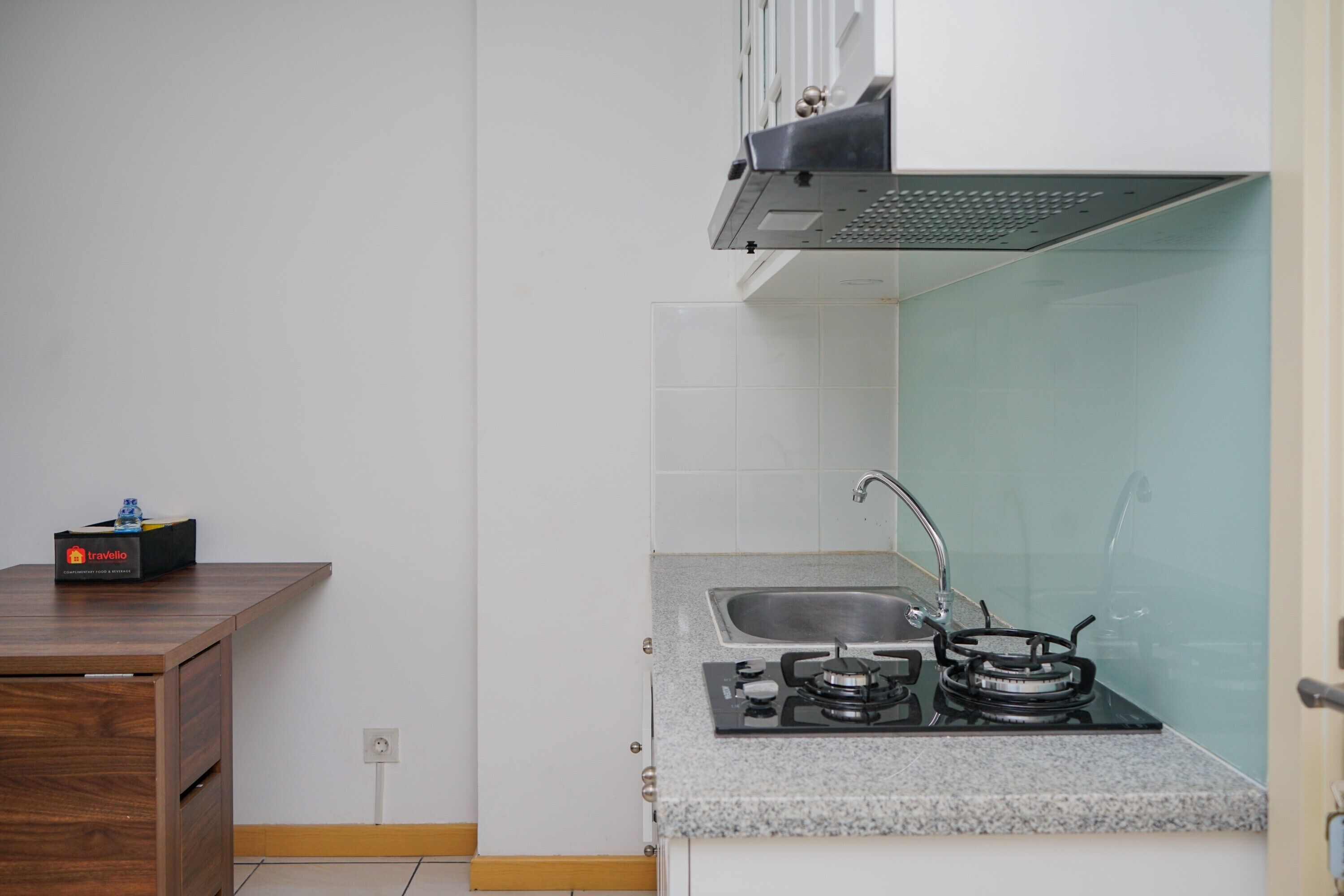 Une cuisine de taille réduite, équipée d’une cuisinière à gaz, d’un évier et d’un petit plan de travail.