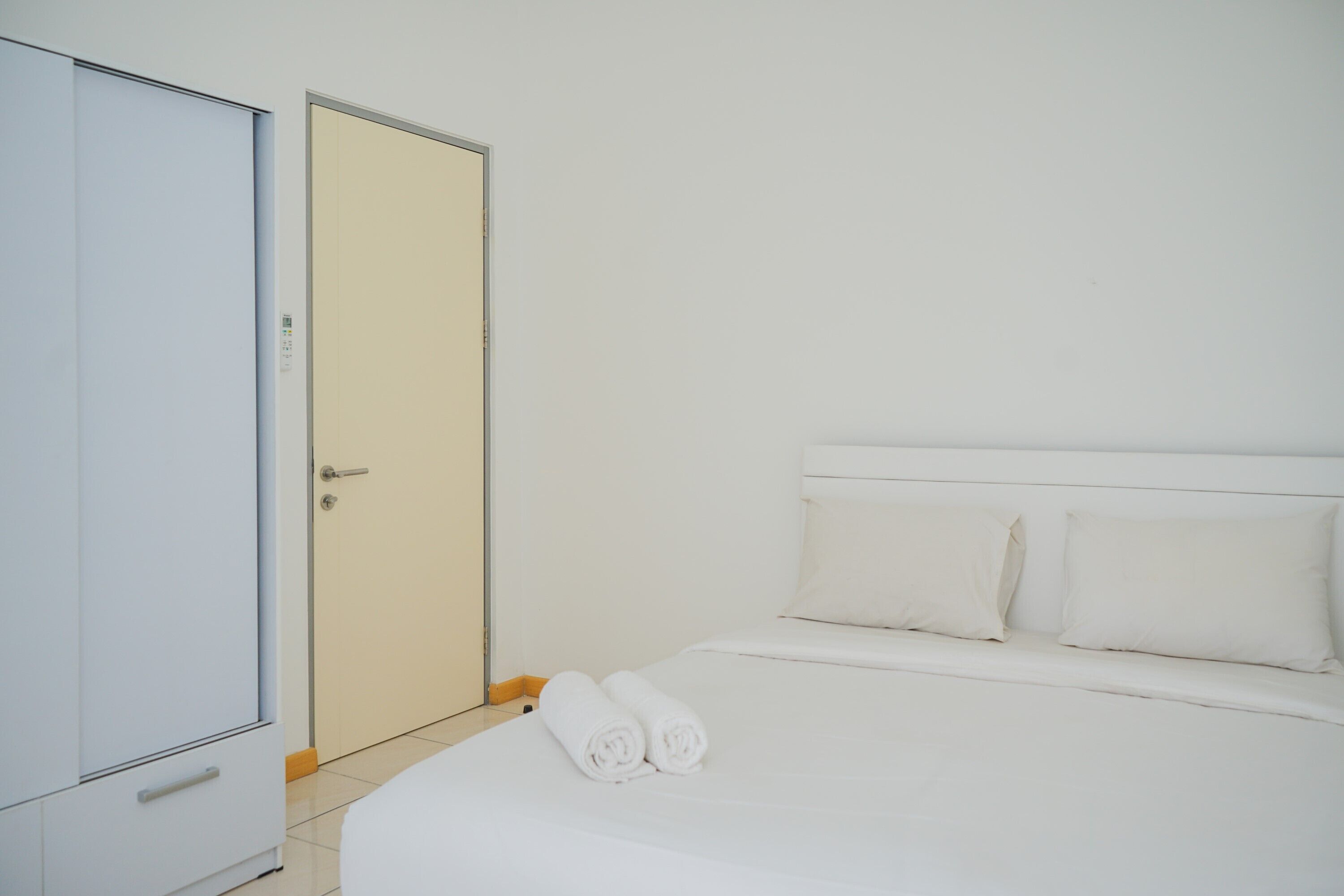 A hotel room with a bed, pillows, and a wardrobe.