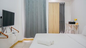 A hotel room with a bed, a desk with a chair, a television, and curtains.