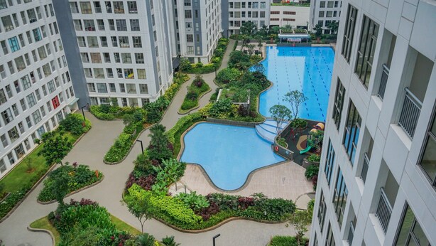 A residential building with a swimming pool surrounded by greenery and pathways.