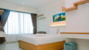 Ein modernes Hotelzimmer mit einem hölzernen Bett, einem blauen Pouf und einem Bild an der Wand.