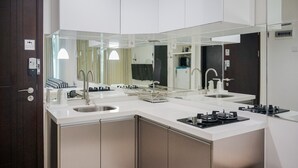 A modern kitchen with a white countertop, stainless steel sink, and a built-in stove. - Cozy Living 1BR at Brooklyn Alam Sutera Apartment (South Tangerang)