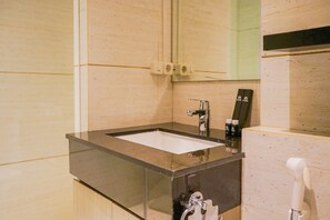 A bathroom with a glass-enclosed sink, a mirror, and a towel rack. - Chic and Spacious 2BR Apartment at Brooklyn Alam Sutera (South Tangerang)