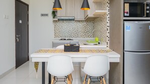 Una cocina moderna con encimera blanca, dos lámparas colgantes, un refrigerador de acero inoxidable y un microondas.